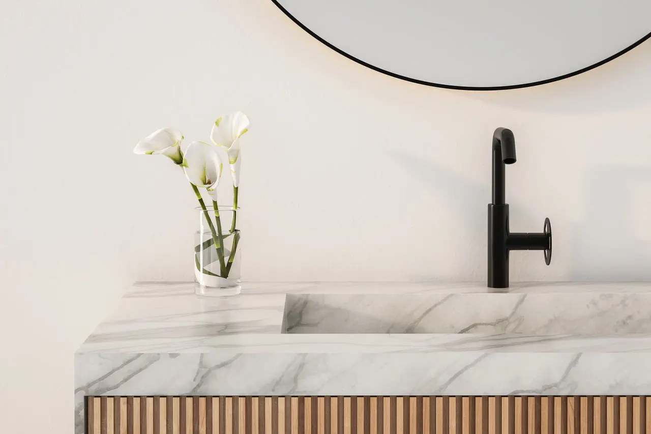 Modern bathroom sink with a marble countertop and black faucet. A small vase with white calla lilies is next to the sink.