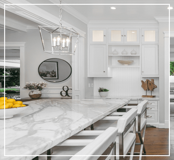 A kitchen with white cabinets and marble counter tops.