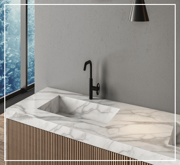 Minimalist kitchen with a marble countertop and integrated sink, black faucet, pendant light, and large window showing trees outside.