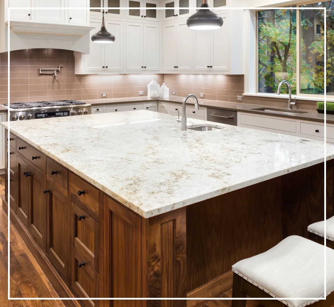 Modern kitchen with white cabinets, stainless steel appliances, and a large marble island with a sink and faucet. Pendant lights hang above the island.