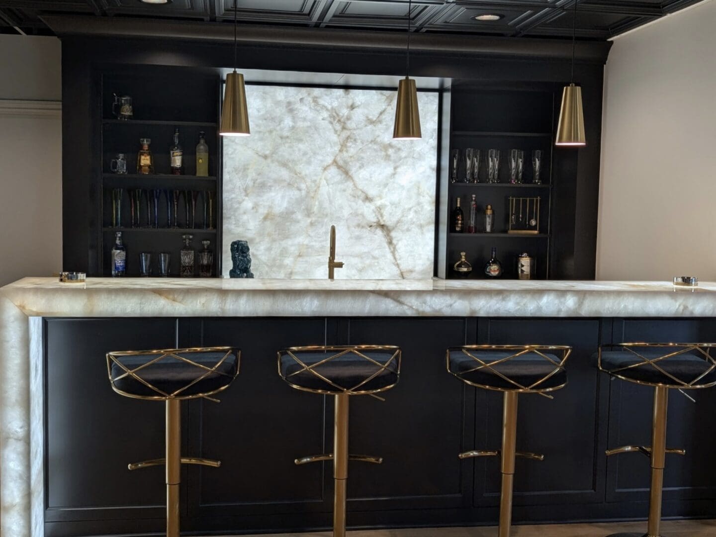 Backlit marble bar with four gold stools