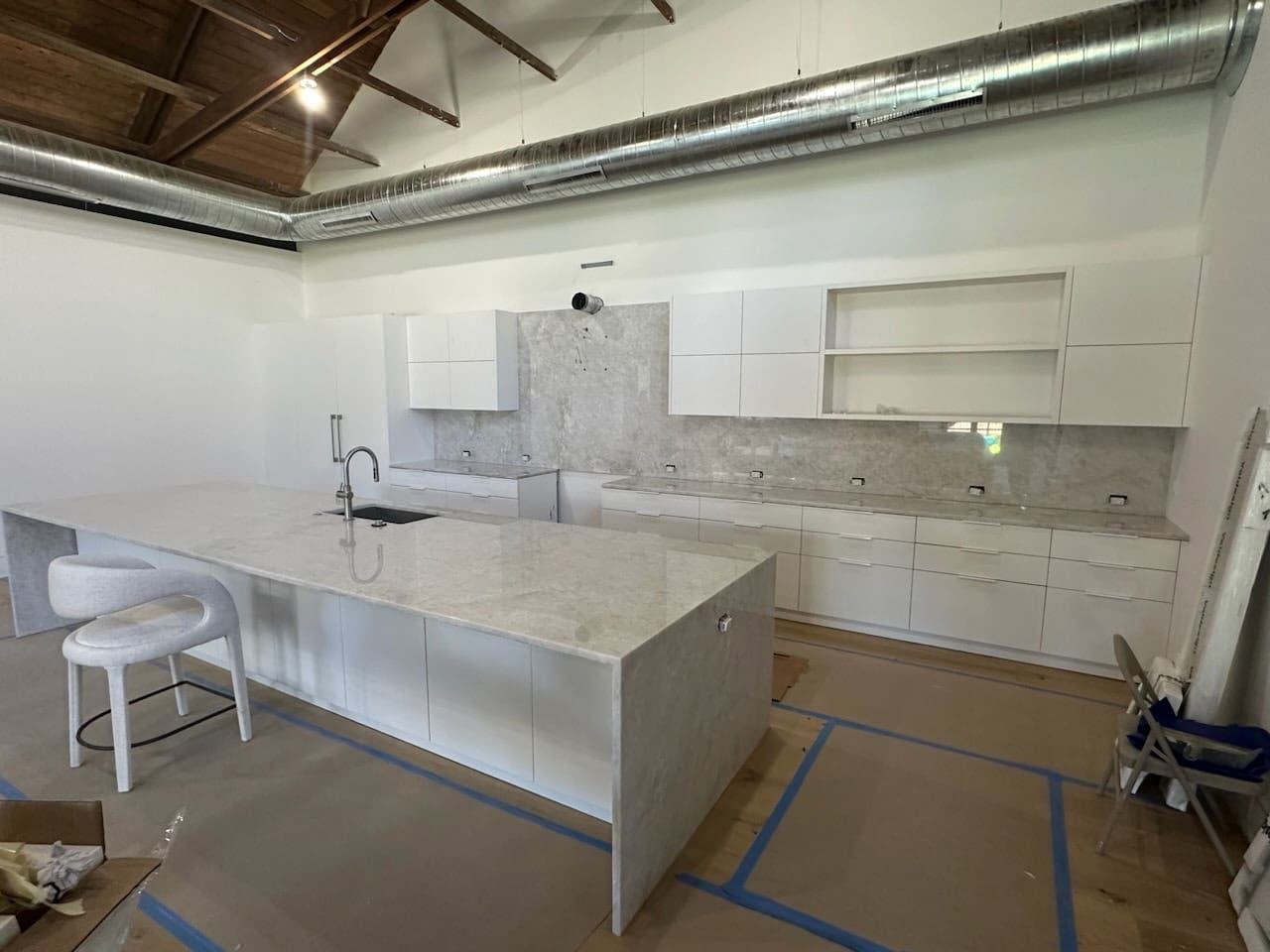 Modern white kitchen with marble island, exposed ductwork