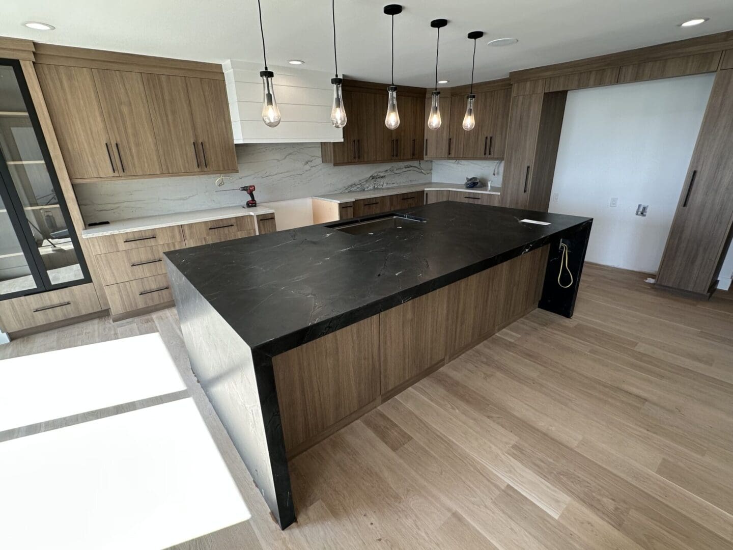 Modern kitchen with black island and pendant lights