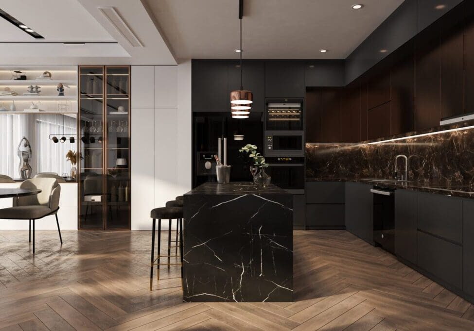 Modern kitchen interior with dark cabinets, a marble island, and wooden herringbone flooring. Dining table with chairs in the background and decorative shelves on the left.